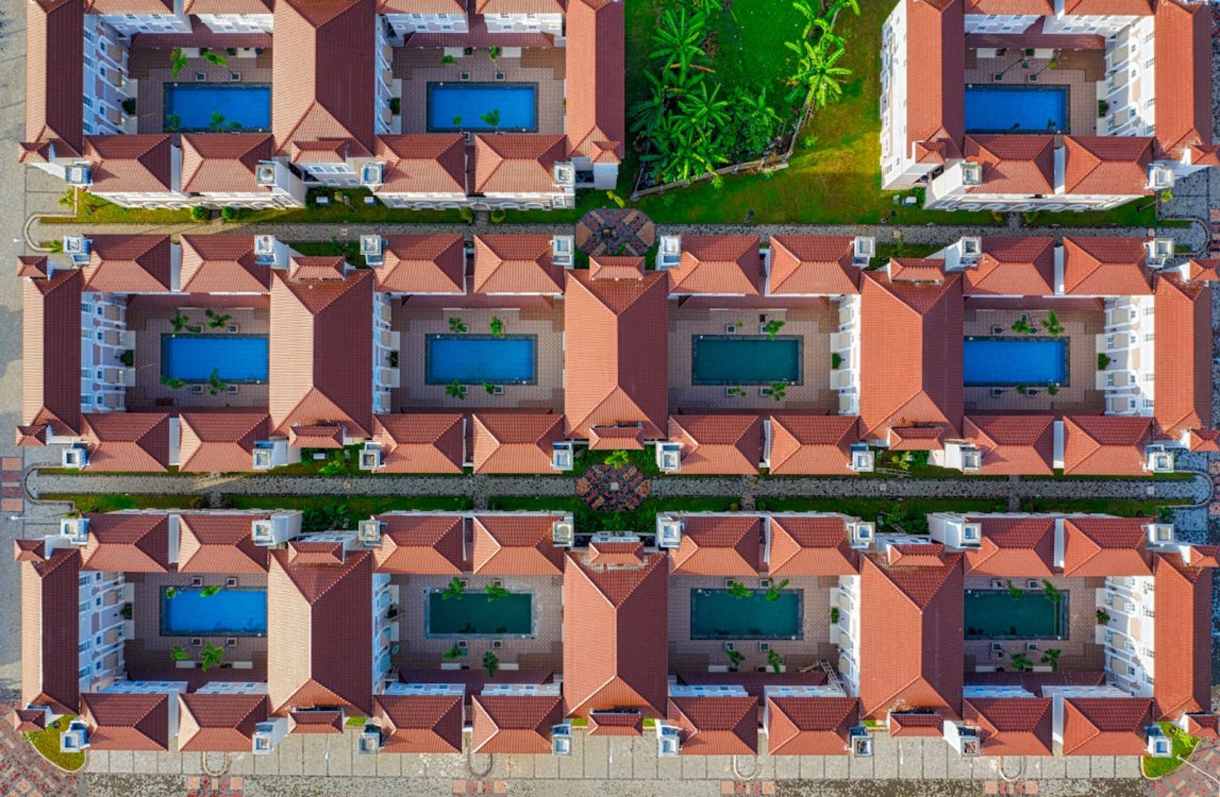 Aerial view of rows of terraced homes with red-tiled roofs and private pools