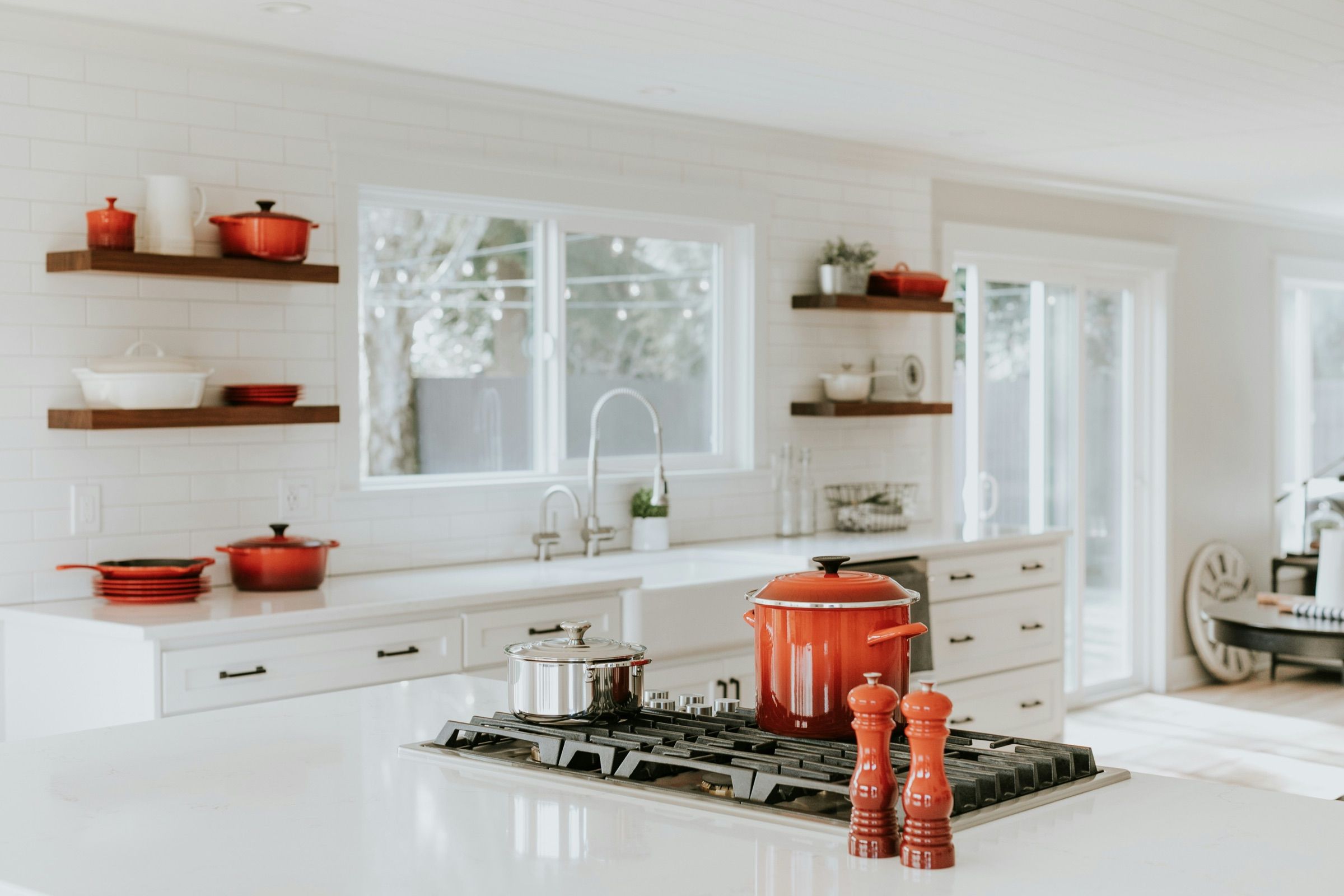 Bright kitchen with white units, open shelves and red cast-iron pans
