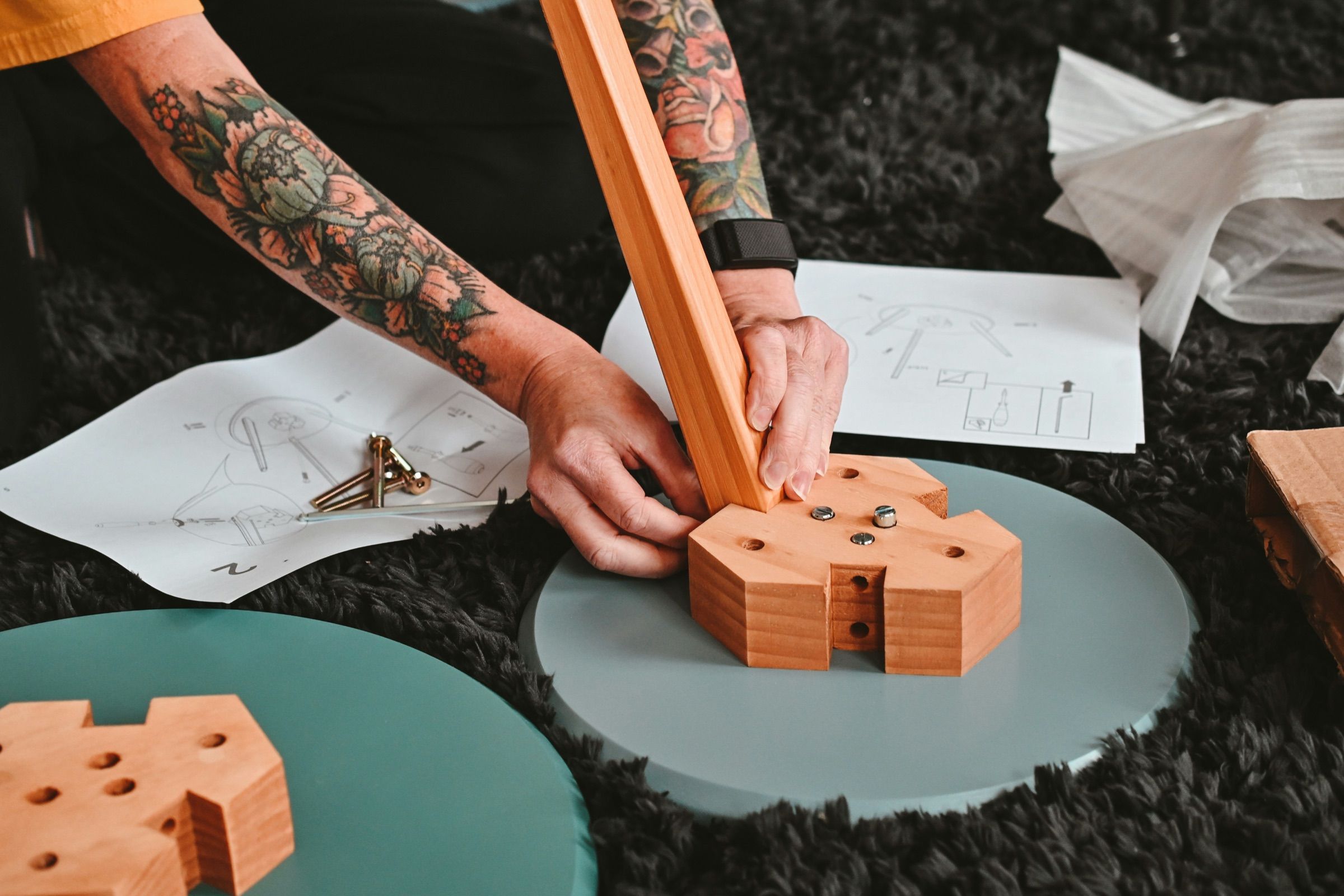 Hands assembling a small wooden piece on a rug during a home repair project