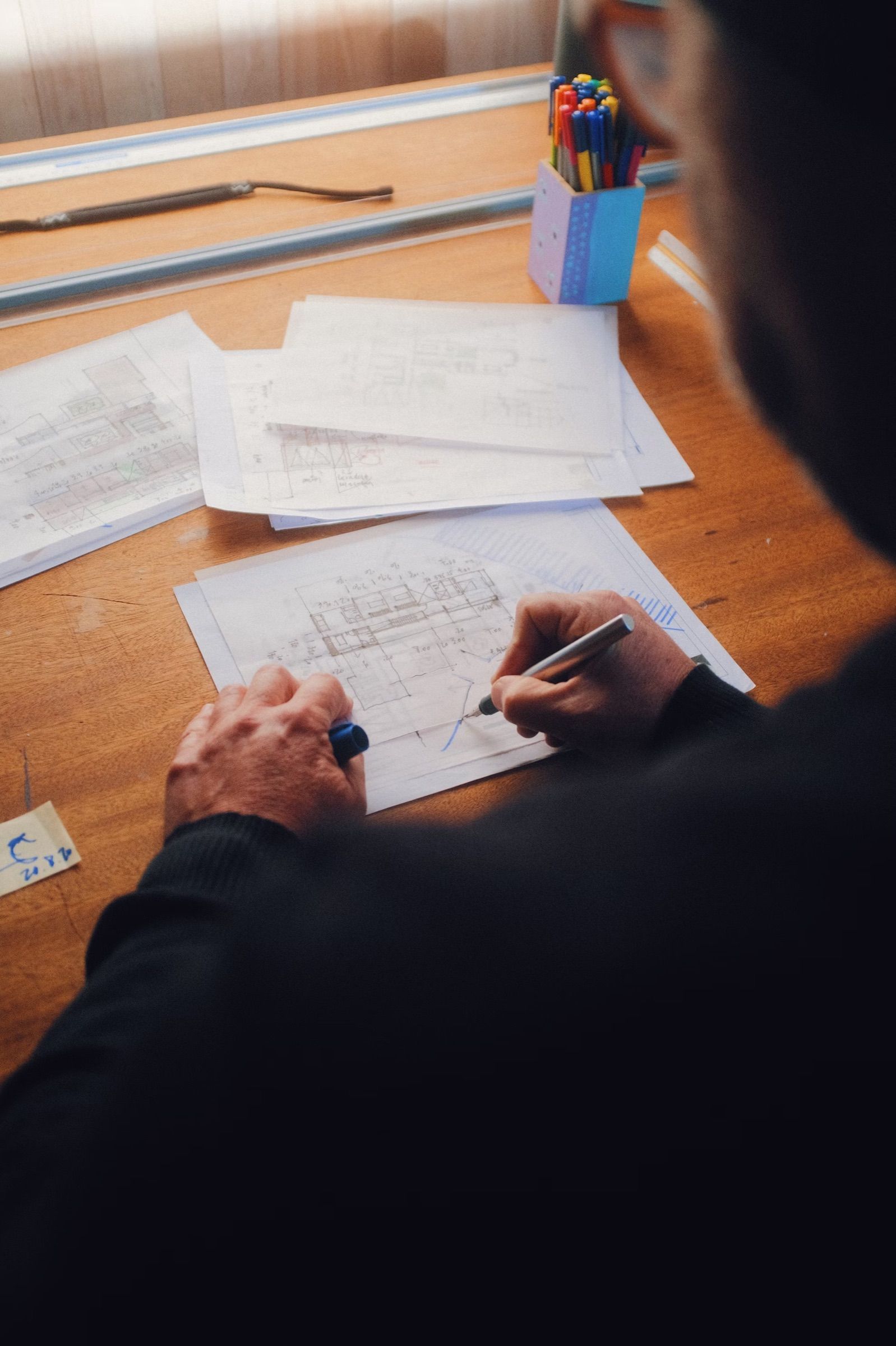 Close-up of a hand marking up printed floor plans with a pen