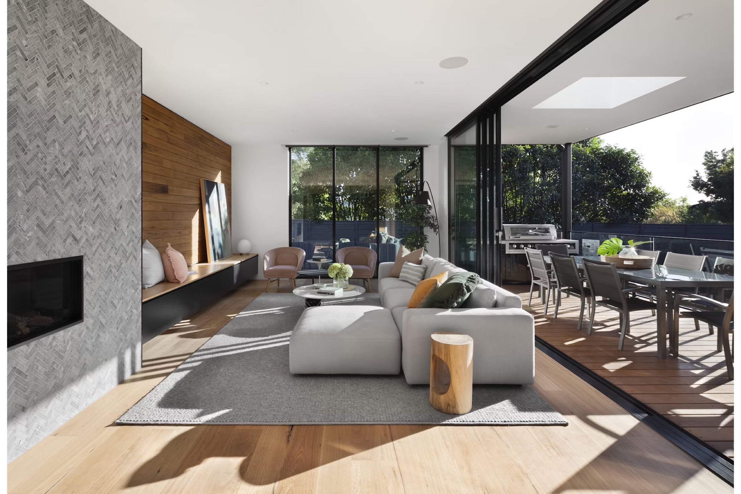 Open-plan living room with a white sofa, fireplace wall and floor-to-ceiling glazing