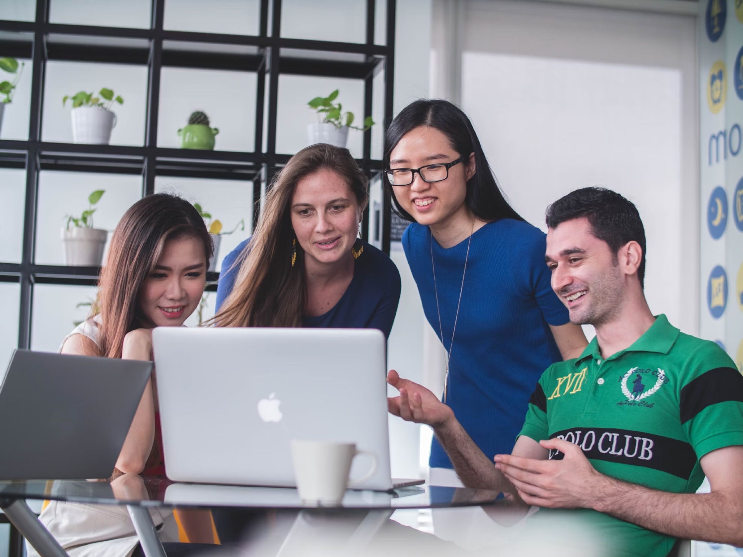Four colleagues gathered around a laptop on an office table